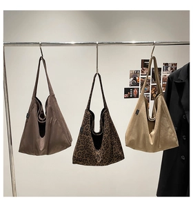 Three oversized tote bags in leopard print, dark brown, and beige hanging on a rack