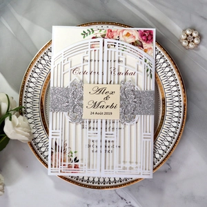 Macro detail of laser-cut wedding invitation featuring a silver glitter belly band