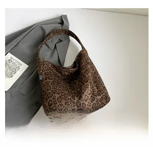 Detail shot of leopard print hobo bag next to a gray blazer and art book in a chic setting