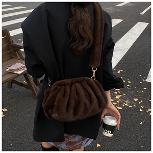 Street style view of dark brown plush cloud crossbody bag with wide fur strap and gold hooks