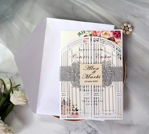 Close-up of laser-cut wedding invitation with floral inner card and silver glitter band