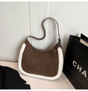Detail of suede crescent bag featuring plush white faux fur trim and adjustable strap