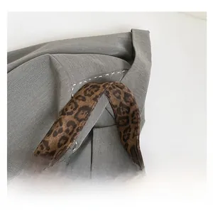 Detail of leopard print handle with white contrast stitching on grey tote bag