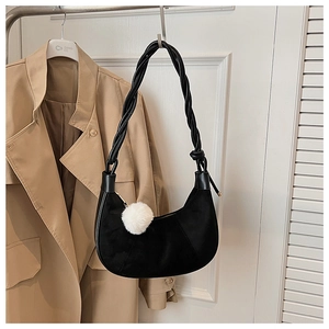 Détail du sac dumpling noir en suède avec bandoulière tressée et pompon en peluche