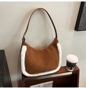 Detail view of brown suede shoulder bag featuring soft white faux fur trim and metal zipper