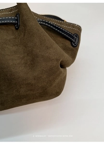 Detail of dark green matte leather tote bag with contrast white stitching and gold zipper