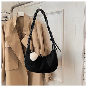 Détail du sac hobo en daim noir avec bandoulière tressée et pendentif en peluche