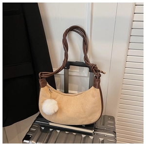 Détail du sac hobo en daim kaki avec poignée tressée et pompon décoratif