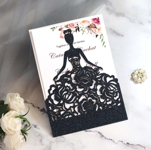 Detail view of laser-cut black glitter invitation featuring a floral dress silhouette