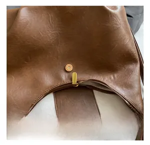 Close-up of brown pebbled leather bag featuring golden zipper and magnetic closure hardware