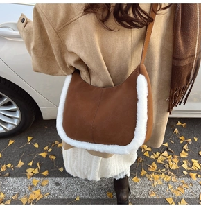 Detail of dark brown faux suede crescent bag with white faux fur trim and leather strap