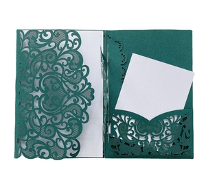 Macro shot of dark green laser-cut wedding card showing intricate vine patterns and inserts
