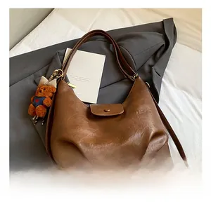 Detail of vintage brown oil wax leather Hobo bag with a cute plush bear charm