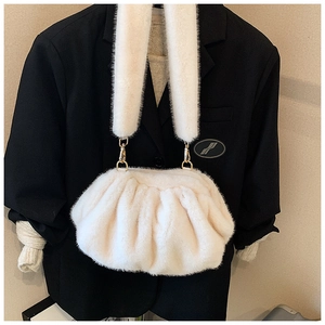 Detail of soft white faux fur cloud bag with plush texture and golden metal hooks