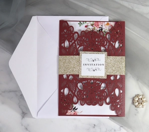 Elegant deep red laser-cut wedding invitation set with floral inner card and gold belly band