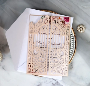 Detailed laser-cut gatefold wedding invitation in champagne gold on elegant marble background
