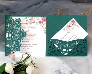 Detail of laser-cut dark green wedding invitation with elegant floral cards and white flowers