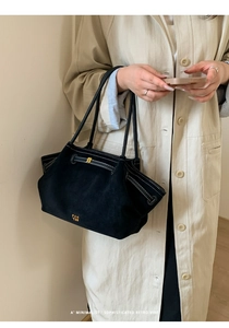 Detailed view of the gold logo branding on a black suede minimalist tote bag for women