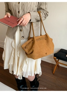 Close-up of brown suede tote bag featuring contrast stitching and leather shoulder straps