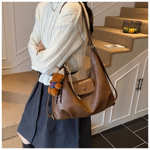 Detail of dark brown faux leather tote bag with pocket and cute bear charm pendant