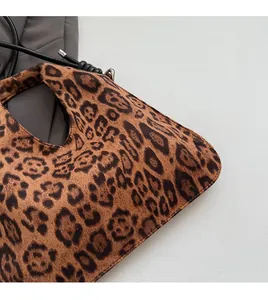 Close-up of leopard print dumpling bag showing soft suede texture and dark grey blazer styling
