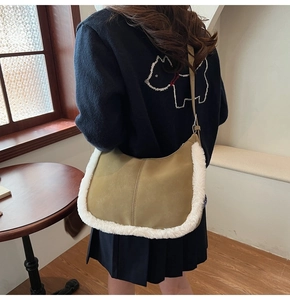 Detail showing plush trim on khaki suede crescent bag worn by a model in soft lighting