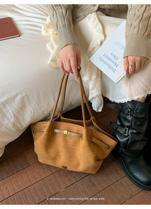 Detail of suede tote bag with golden buckle and refined pleats in a retro lifestyle setting
