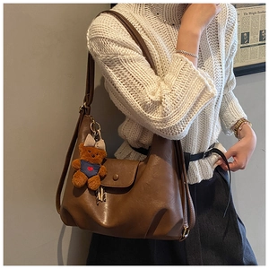 Detail view of brown vintage PU leather tote with a cute teddy bear plush charm