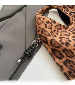 Close-up of leopard print bag featuring gold metal rings and black woven leather charm