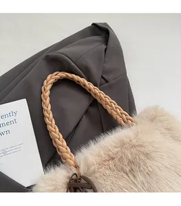 Close-up of beige plush tote bag with brown woven leather strap and letter charm