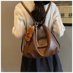 Close-up of vintage brown leather tote bag with a cute plush bear charm on the back