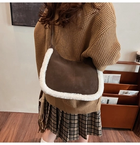 Detail of brown suede hobo bag with white faux fur trim and vertical stitching details