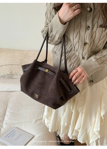 Detail of dark brown suede tote bag with drawstring belt and golden hardware buckles