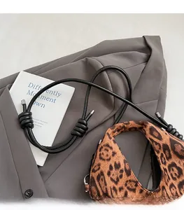 Detail of leopard print faux fur texture with black leather strap and silver metal tip