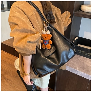 Detail of black large capacity leather tote bag with a cute brown bear charm