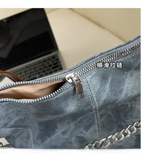 Close-up of smooth silver zipper and metal chain detail on vintage denim backpack