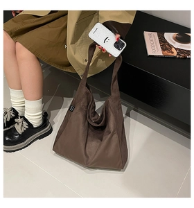Close-up of brown suede tote bag featuring minimalist soft structure and side woven label