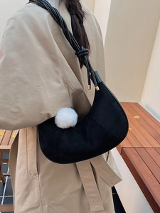 Sac croissant minimaliste en daim noir avec bandoulière tressée et pompon blanc doux