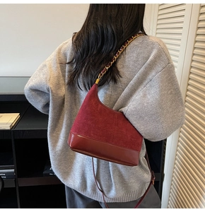 Detail of burgundy dumpling bag showing suede and patent leather texture on a shoulder