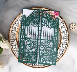 Detail of laser-cut green wedding invitation card with pink floral insert on marble