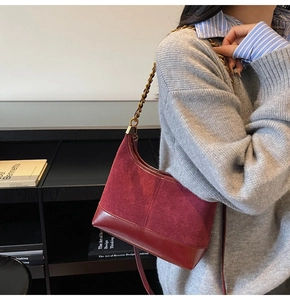 Close-up of a red pleated dumpling bag with elegant gold chain and textured leather finish