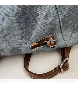 Detail of washed denim texture with silver heart pendant and brown leather strap on bag