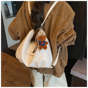 Minimalist white leather backpack with a cute teddy bear charm shown on a model