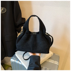 Detail of black suede pleated bucket bag featuring metallic rings and leather buckle closure