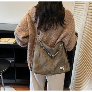 Retro washed olive hobo bag with chunky silver chain shown on shoulder with knitwear