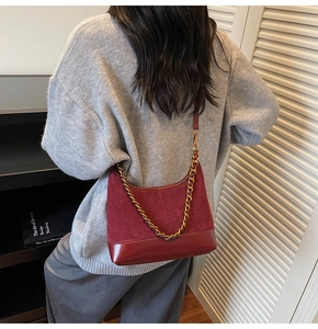 Detail of burgundy patchwork hobo bag with a gold chain strap and suede texture