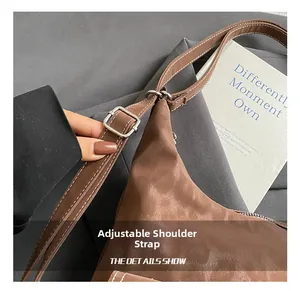 Detail of adjustable shoulder strap with silver metal buckle on brown faux leather bag