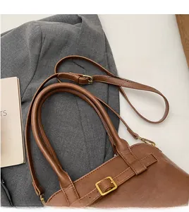 Detail of adjustable long shoulder strap and golden buckle on brown vintage tote bag