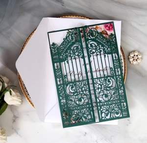 Macro detail of laser-cut gate-fold wedding invitation in dark green with floral inner card