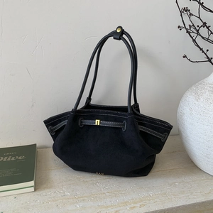 Close-up of black suede tote bag featuring white contrast stitching and gold hardware